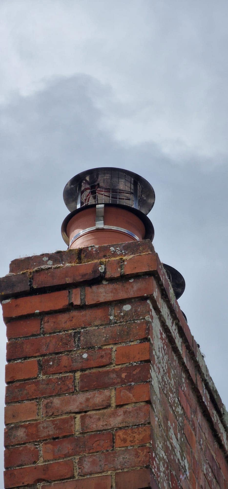 A brick chimney stack with its cowl, seen from below
