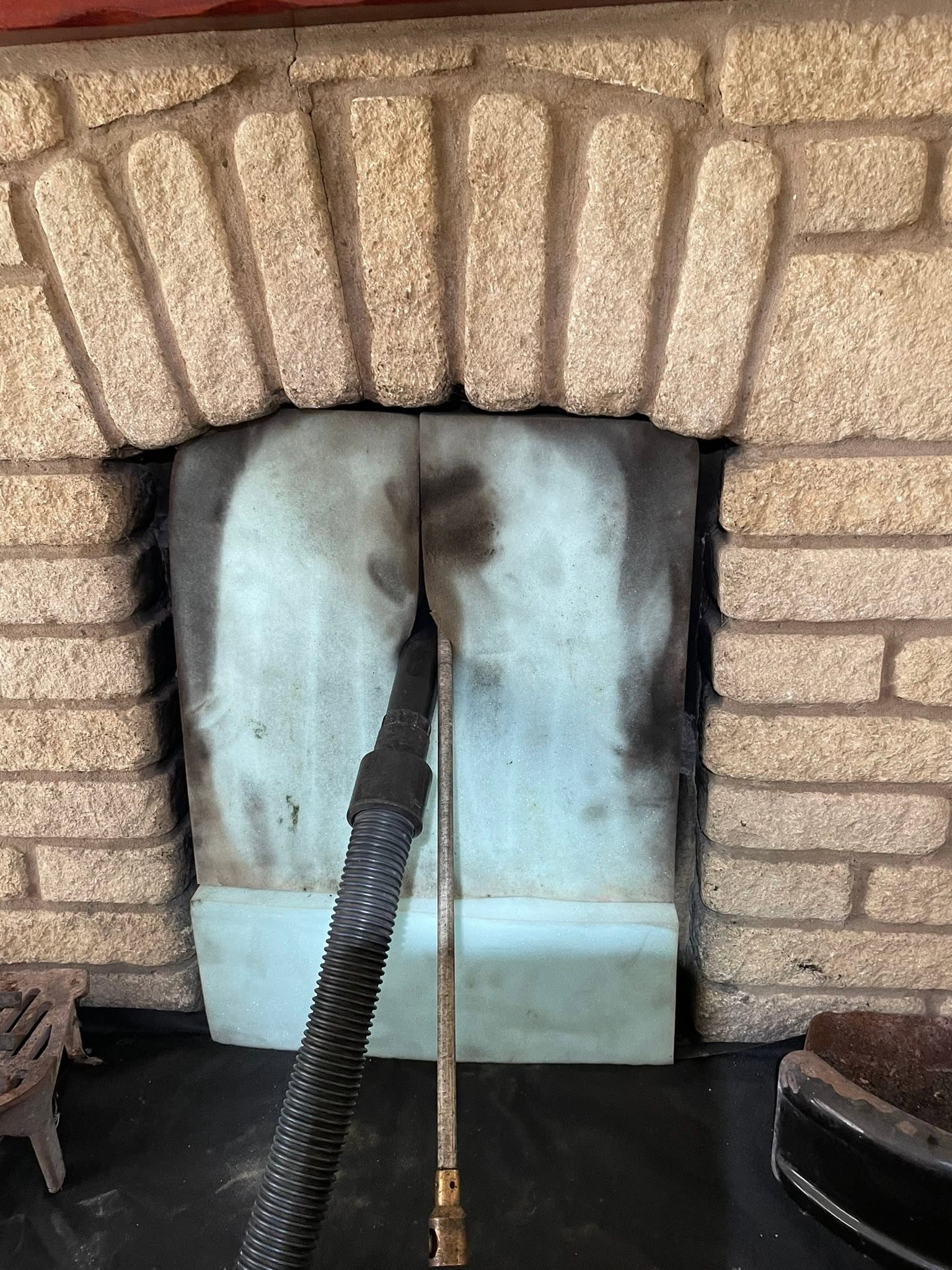 A fireplace sealed with a sheet and the vacuum hose in place before sweeping