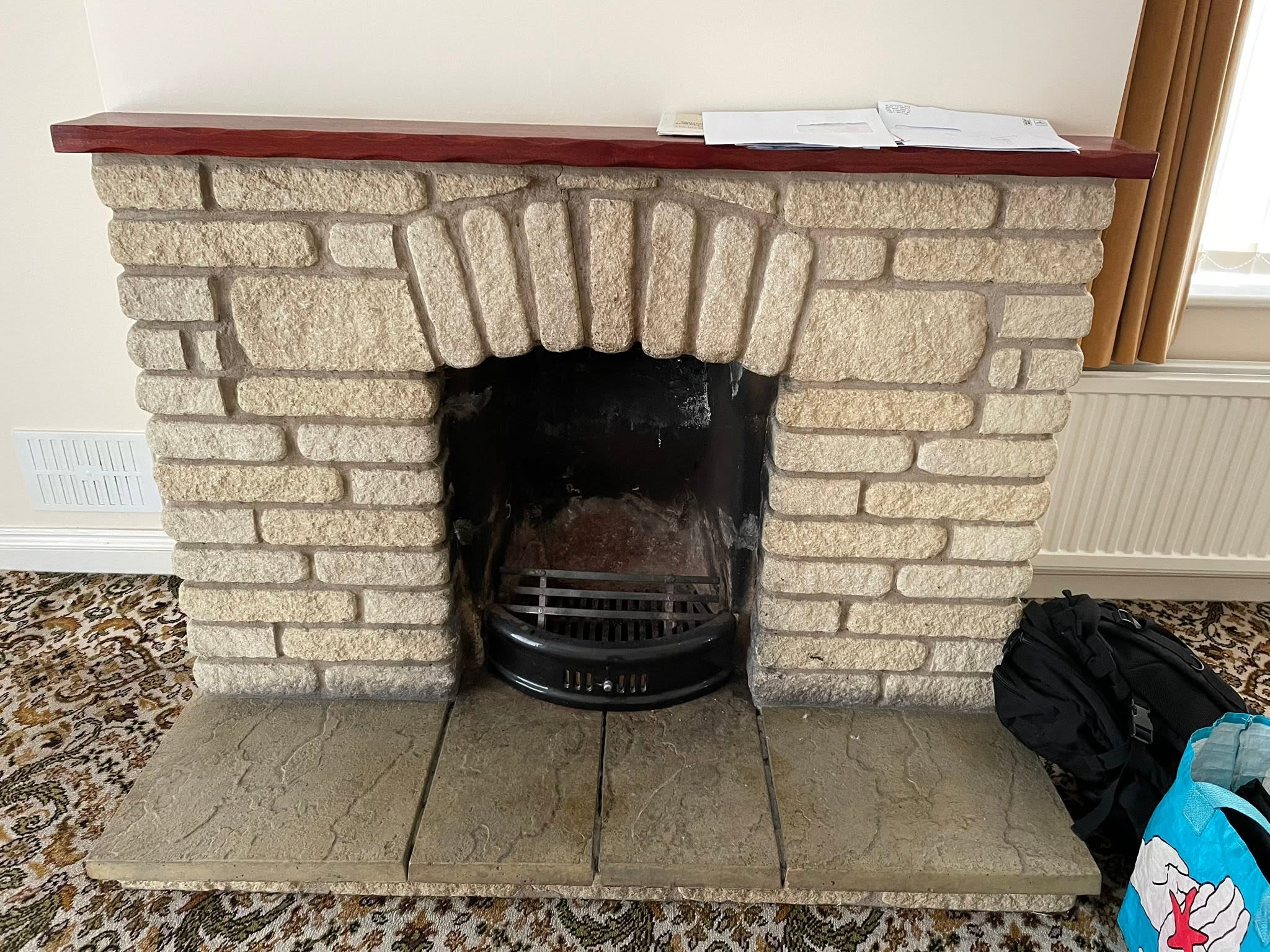 A stone fireplace with an open grate in a sitting room