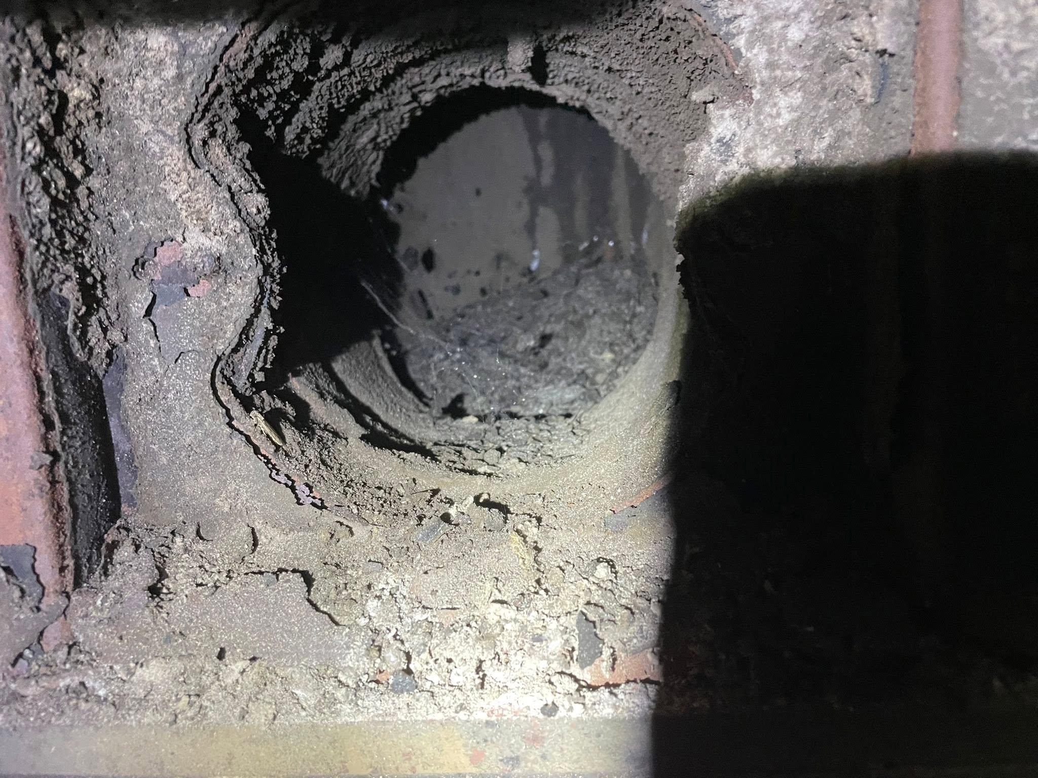 A stove flue outlet coated in soot before sweeping