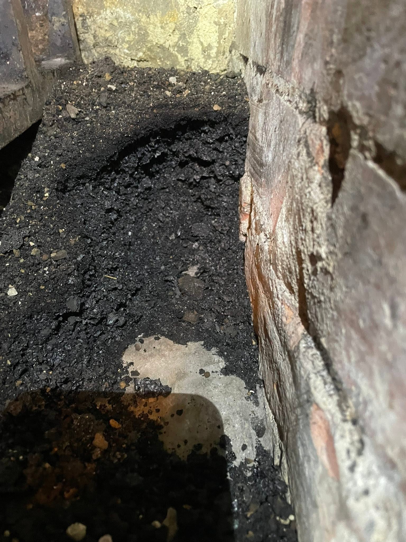 Thick soot built up on a smoke shelf beside the brickwork