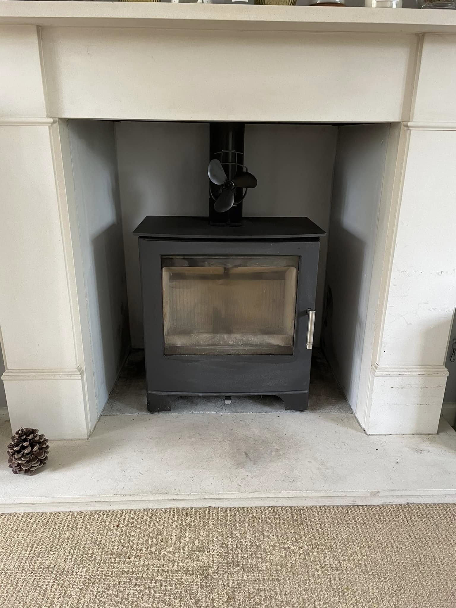 A modern stove in a white fireplace surround after sweeping