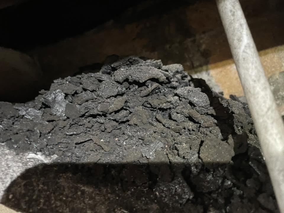 Flakes of soot piled on a stove baffle