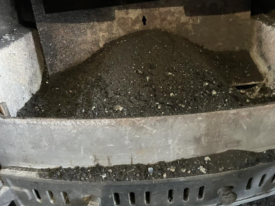 Soot piled in the firebox of a stove before cleaning