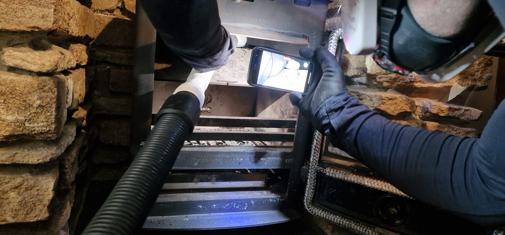 A CCTV camera check of a flue, the picture showing on a phone screen beside the vacuum hose